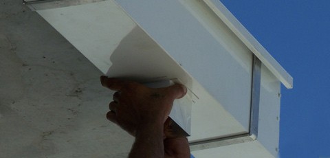 An aluminium box gutter and downpipe being assembled and installed on-site.